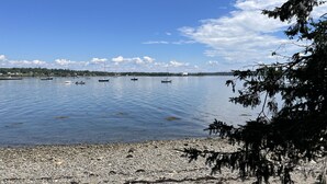 Un lago tranquilo con barcos, una orilla rocosa y un cielo despejado.