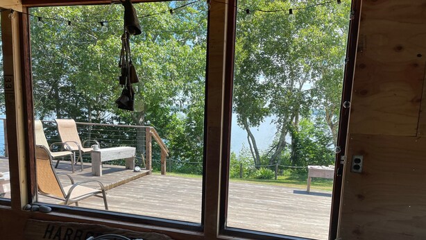 Una terraza de madera con vistas a un lago, una mesa con una cesta y un cartel que dice "HARBOR WEST".