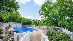 Um quintal com piscina, cadeiras de deck e cerca branca.