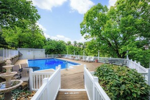 Ein Garten mit Swimmingpool, Liegestühlen und einem weißen Zaun.