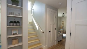Una escalera que conduce a una puerta, con estantes a ambos lados que exhiben objetos decorativos.