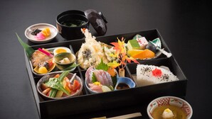 A traditional Japanese bento box with various sushi and side dishes, accompanied by chopsticks and a small bowl of soup. - Sky Hotel Namerikawa (Namerikawa)