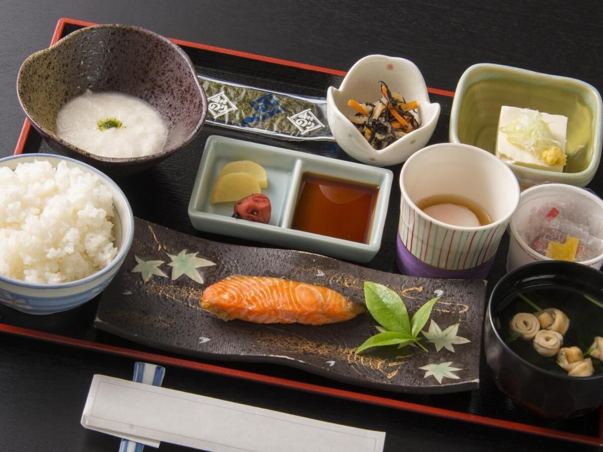 Un repas japonais traditionnel composé de riz, de saumon et de divers accompagnements, le tout présenté sur un plateau.