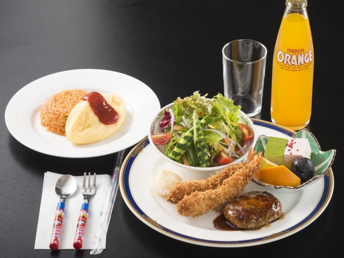 Ein Tisch mit Speisen, einer Orangensaftflasche und Besteck.