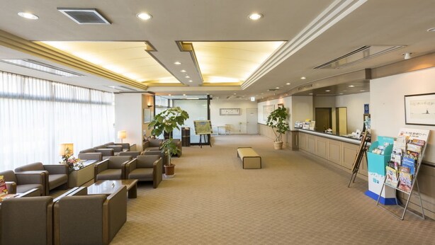 A hotel lobby with seating areas, a reception desk, and informational posters. - Sky Hotel Namerikawa (Namerikawa)