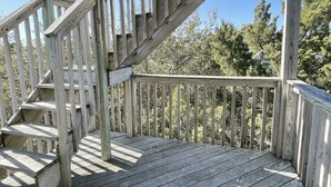 Une terrasse en bois avec un escalier en colimaçon menant à un niveau supérieur.