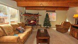 Una sala de estar acogedora con chimenea de piedra, un árbol de Navidad, un sofá y una mesa de centro.