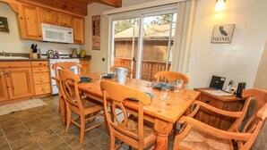 Una cocina con armarios de madera, un microondas y una mesa de comedor con sillas.