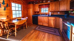 A wooden cabin interior with a kitchen, dining area, and a sign for Knutson Property Services LLC.