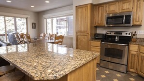 A kitchen with granite countertops, wooden cabinets, a stainless steel oven, and a microwave. - Spacious Town Home with Ski-In/Ski-Out Access (Whitefish)