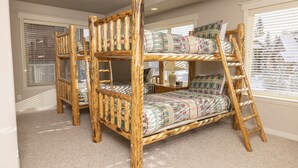 A bunk bed with a ladder, a nightstand, and a window with blinds. - Spacious Town Home with Ski-In/Ski-Out Access (Whitefish)