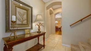 A hallway with a wooden console table, a framed artwork, a lamp, and a staircase. - Tropical Villa w/Beach Club Access ★Quiet Location★Bikes and Beach Gear★Walk to Restaurants (Kamuela)