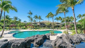 Ein Resort mit einem großen Pool, umgeben von Palmen und einem Gebäude mit mehreren Balkonen.