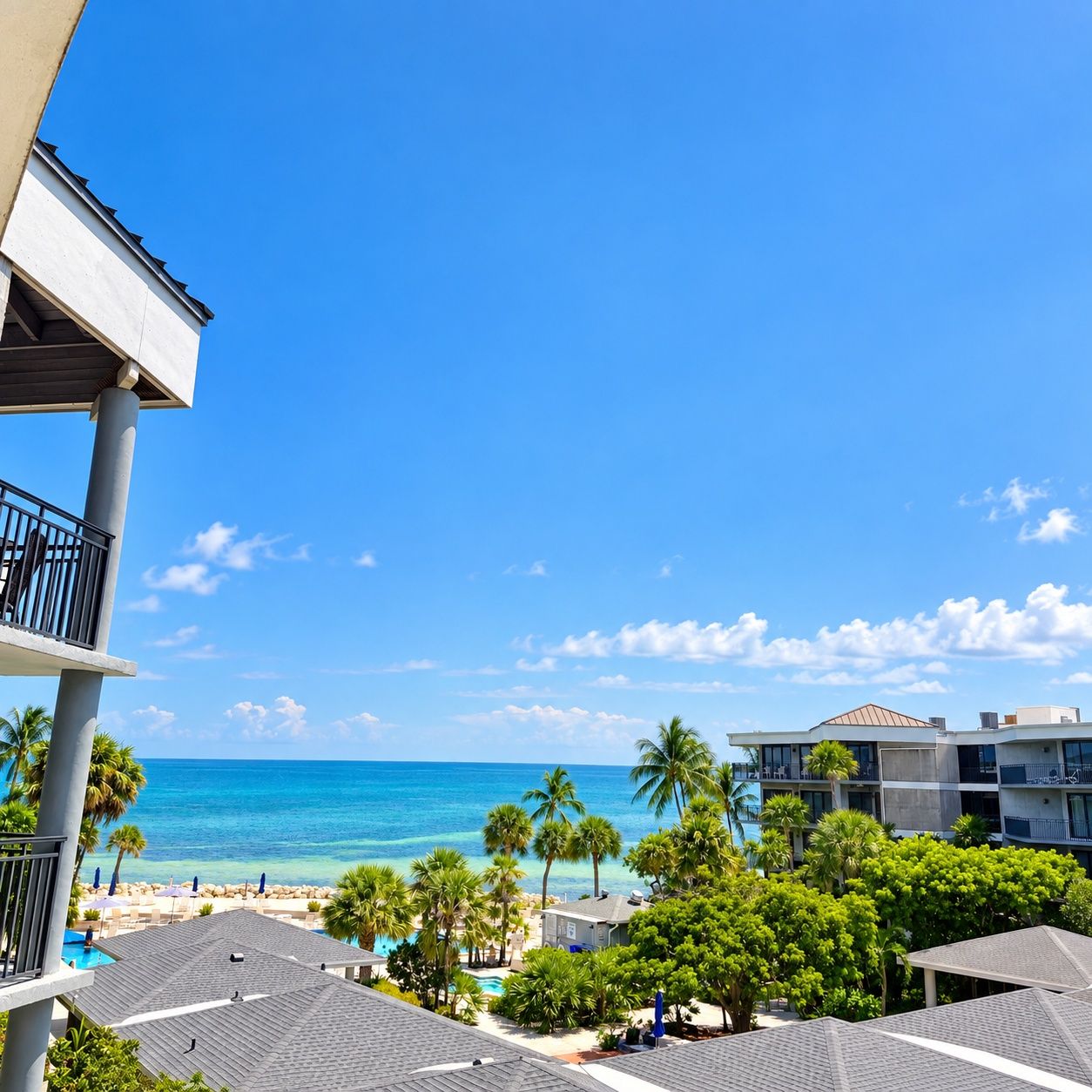 A resort with a view of the ocean, palm trees, and a pool area.