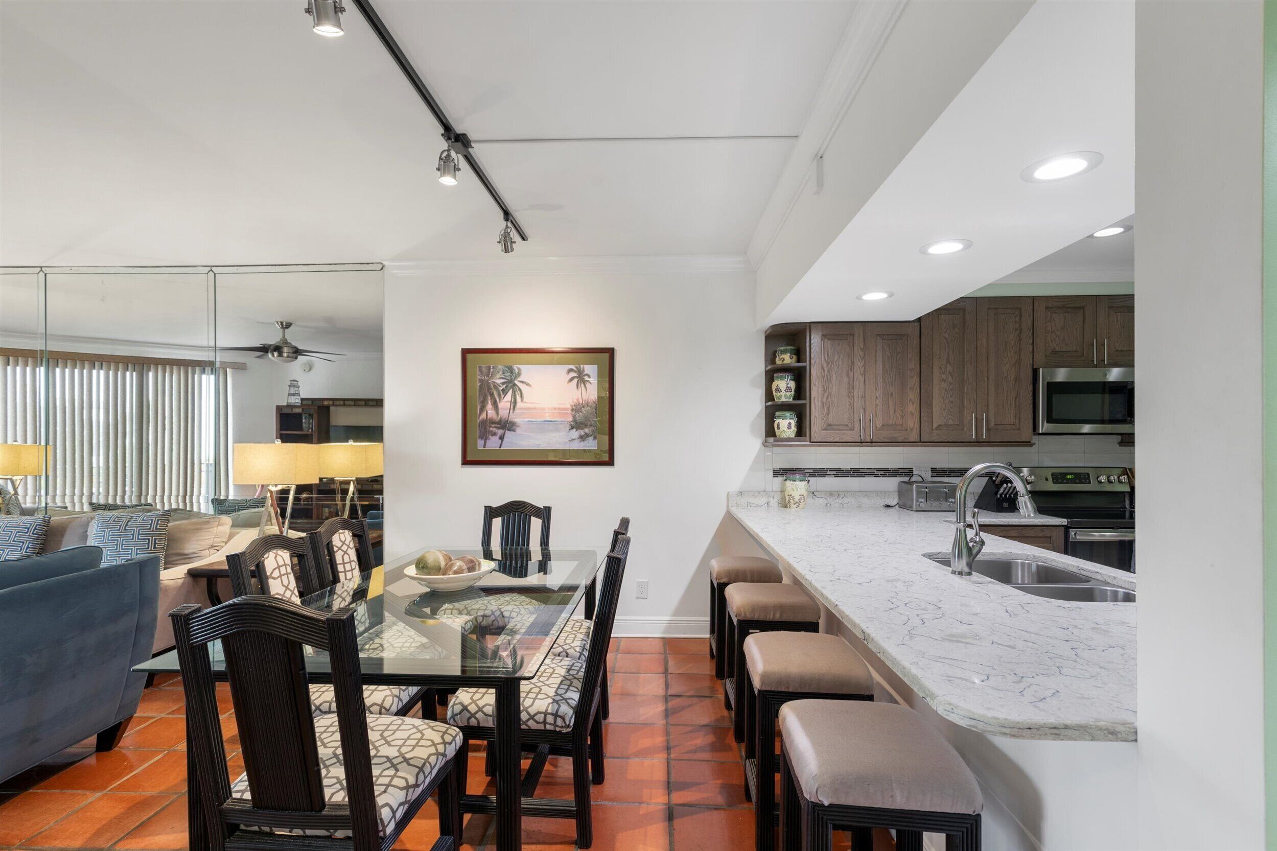 A modern kitchen with a marble countertop, built-in cabinets, and a stainless steel refrigerator.