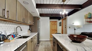 Una cocina moderna con armarios de madera, encimera de mármol y una isla grande con un cuenco decorativo.