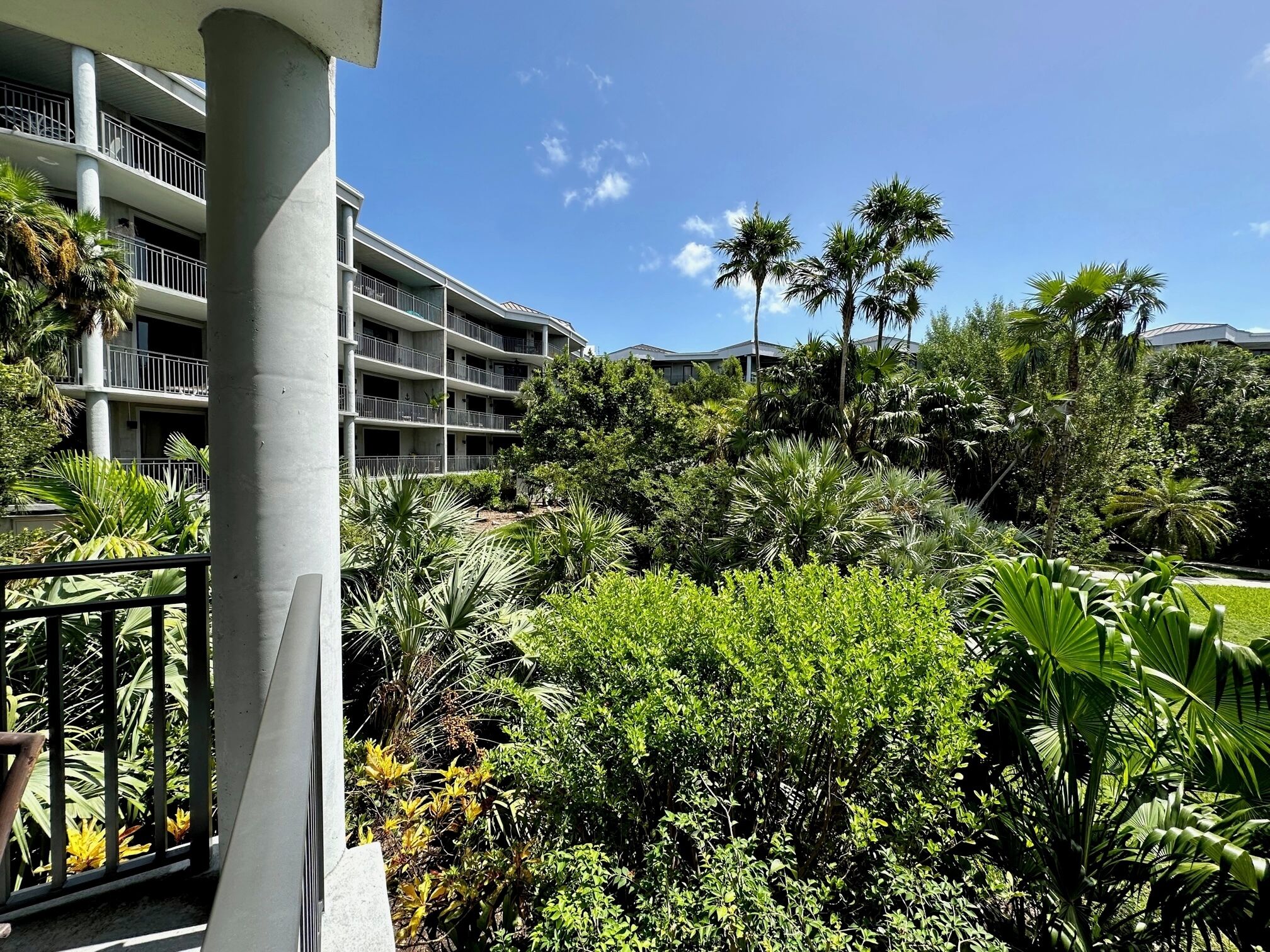 A multi-story hotel with balconies, surrounded by lush tropical vegetation and palm trees.