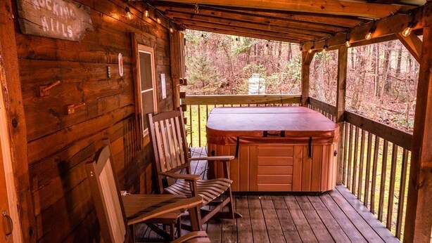 A wooden cabin with a hot tub, wooden deck, and a sign that reads "Rocking Hills." - The Retreat - Cozy studio cabin - Hot Tub, Firepit, pond, natural playground (Logan)