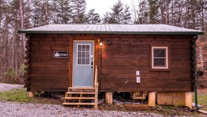 A small wooden cabin with a door, a window, and a sign on the door. - The Retreat - Cozy studio cabin - Hot Tub, Firepit, pond, natural playground (Logan)
