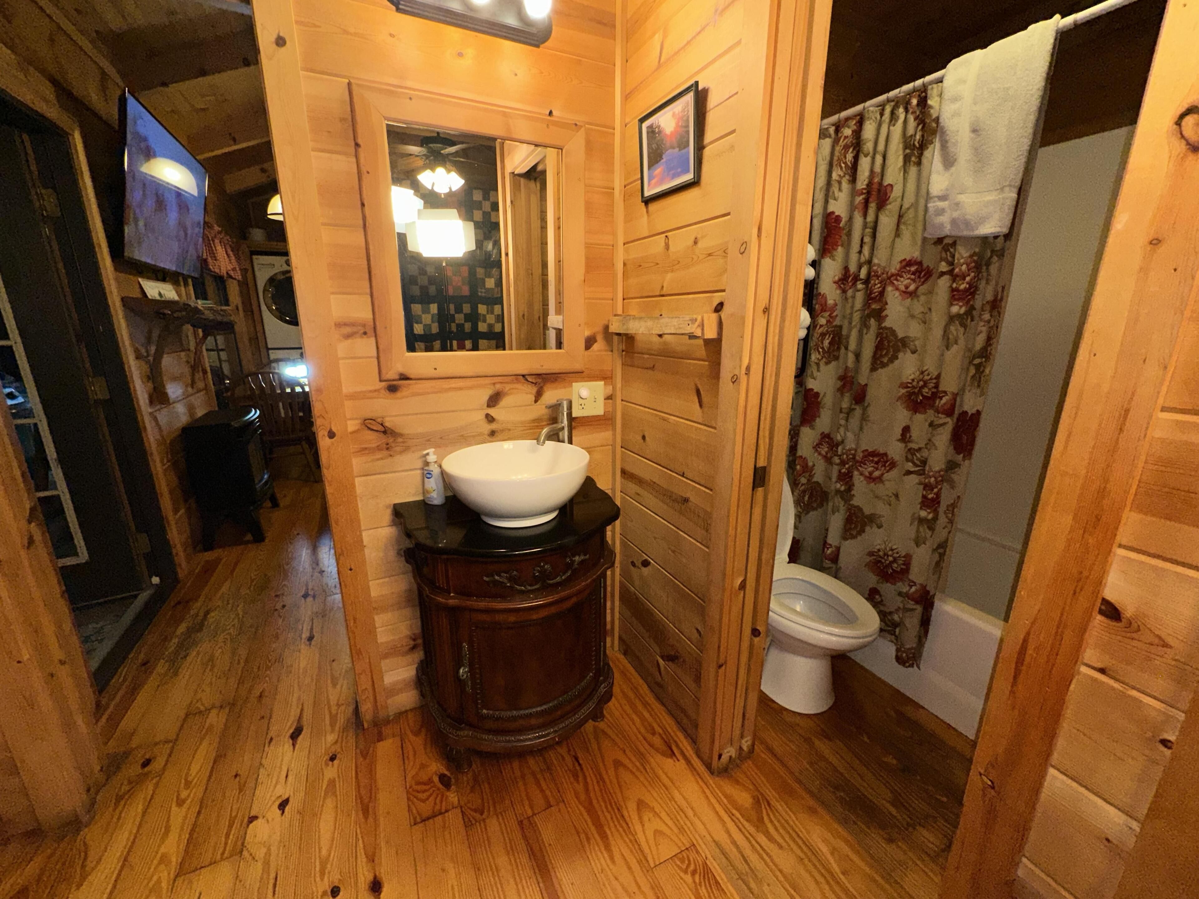 Een houten interieur met een wastafel, spiegel en toilet.