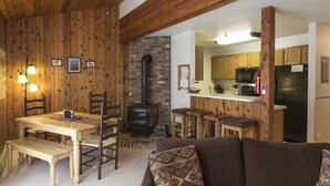 L’intérieur chaleureux d’un chalet comprend un coin repas, une cheminée, une cuisine et un salon avec un canapé.