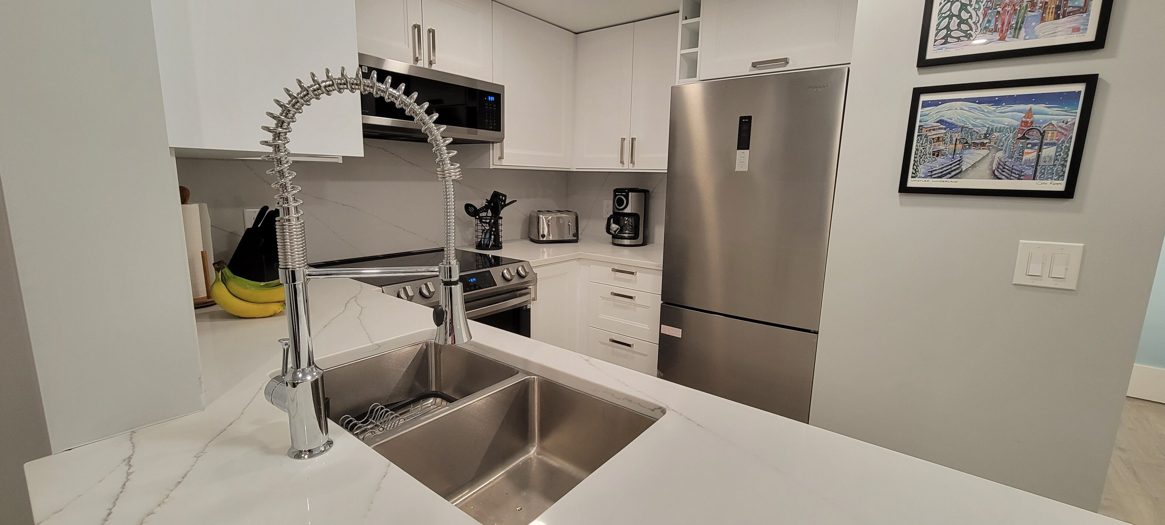Una cocina moderna con un lavamanos de acero inoxidable, un horno empotrado y un refrigerador.