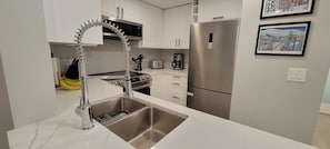 A modern kitchen with a stainless steel sink, a built-in oven, and a refrigerator.