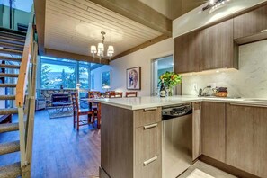 A modern kitchen with wooden cabinets, a built-in dishwasher, and a large window.