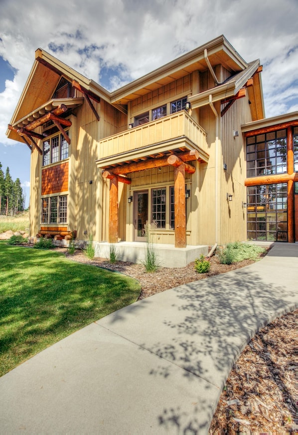 A modern two-story house with a large front porch, large windows, and a stone foundation.