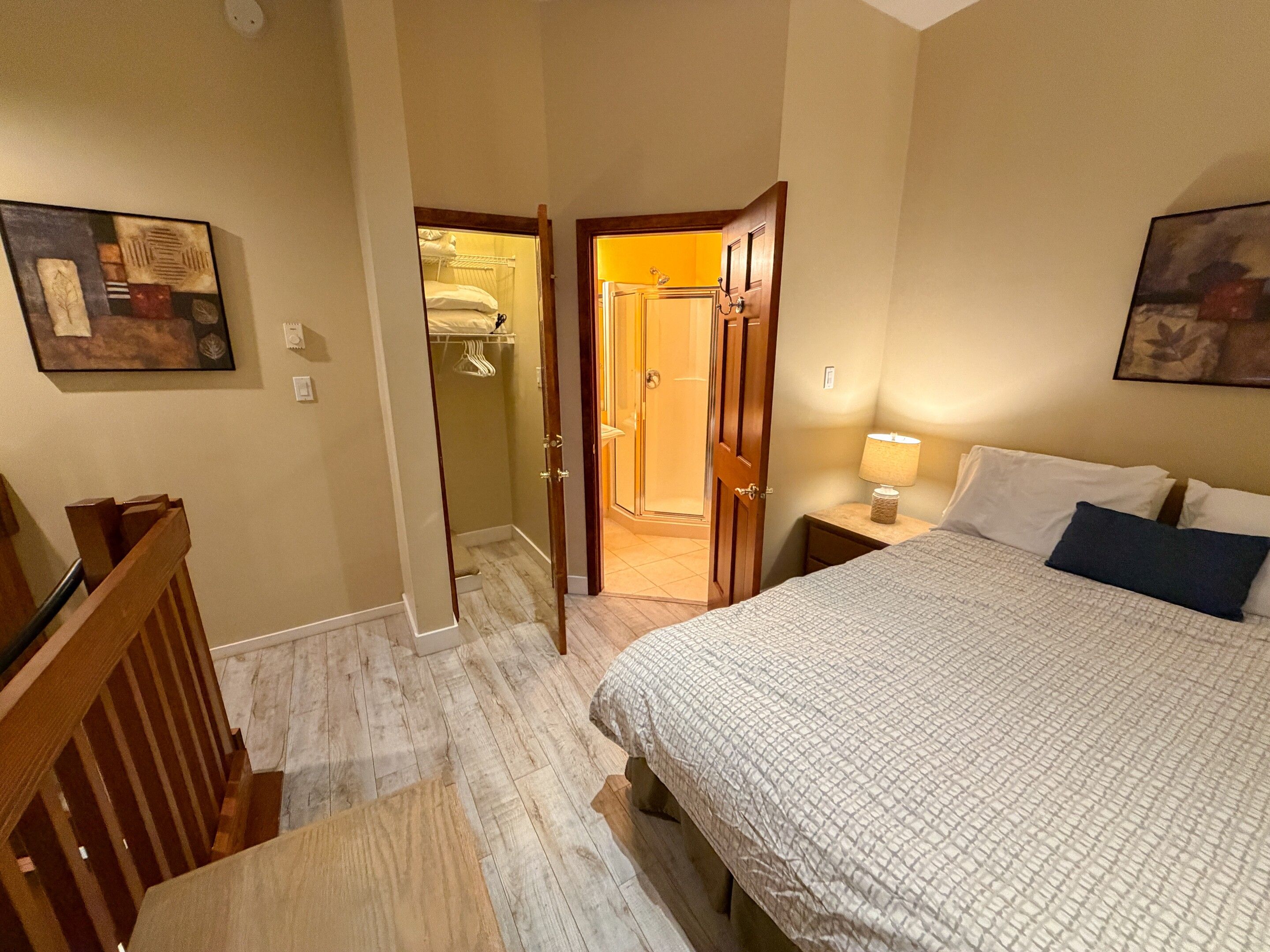 A hotel room with a bed, bedside lamp, and a shower area.