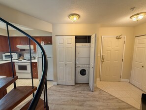 A laundry room with a washer and dryer, a microwave, and wooden cabinets. - On Blackcomb Mountain - Balcony w/ BBQ, Common Rooftop Hot Tub, Free Parking (Whistler)