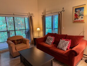 A living room with a red sofa, a beige armchair, and a wooden coffee table.