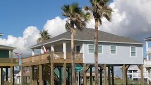 A beachfront house with a balcony, palm trees, and a clear sky. - Shore Haven - 2 Bedrooms, 2 Bath, Sleeps 10 - Beach Front! (Crystal Beach)