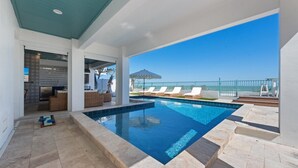 Une piscine avec des chaises longues et vue sur l’océan.