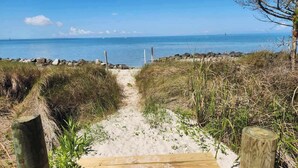 A sandy beach path leading to the ocean with a wooden boardwalk and wooden posts. - Secret Cedars: Soundfront, perfect kayaking or water activities. (Ocracoke)