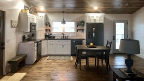 A spacious kitchen with wooden cabinets, a dining area with a table and chairs, and a chandelier. - The PearTree Cottage- enjoy the view in the hot tub! 10 minutes from Berlin (Dundee)