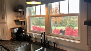 A kitchen with two sinks, a coffee maker, and a window with a view of a garden. - The PearTree Cottage- enjoy the view in the hot tub! 10 minutes from Berlin (Dundee)