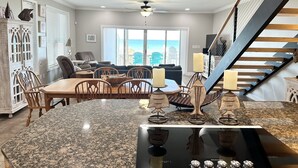 A modern kitchen with granite countertops, a built-in stove, and pendant lighting. - “Dolphin Watch” Amazing Gulf Front Home, Elevator, Paddleboard! (Navarre Beach)