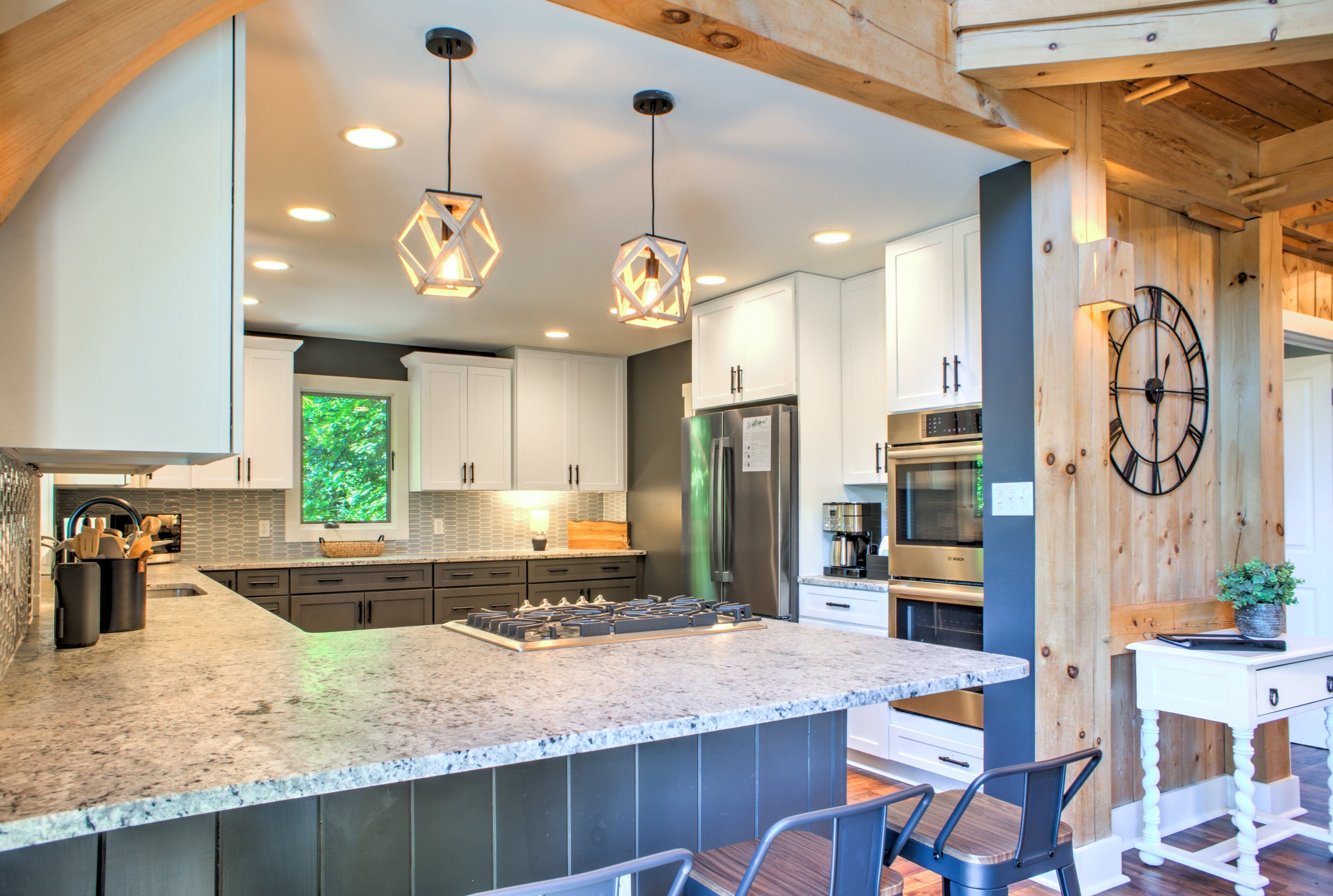 A modern kitchen with a large island, stainless steel appliances, and pendant lighting.