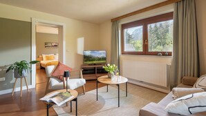 A modern living room with a television, seating area, and a window with curtains. - "Stylish and Comfortable One bedroomed Apartment in söll - Sleeps up to 4!" (Söll)