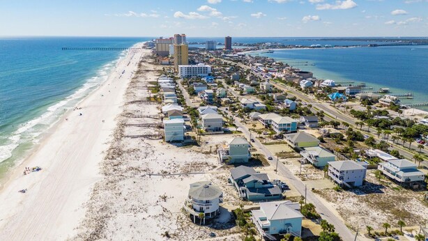 Vista aérea de una zona residencial costera con casas, una playa y un muelle.