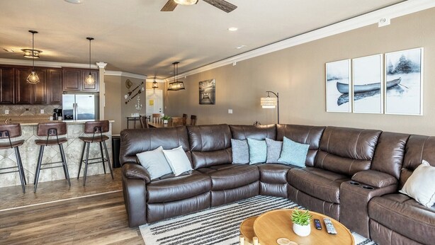 Een moderne woonkamer met een hoekbank, een eethoek en een keuken met barstoelen.