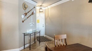 Een eetgedeelte met een houten tafel, een stoel, een tafel met glazen blad en sportattributen aan de muur.