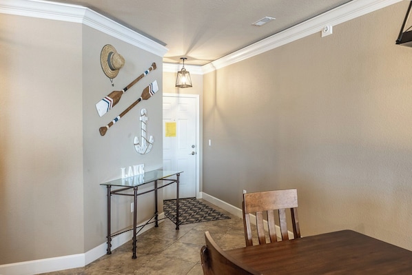 Un espace repas comprenant une table en bois, une chaise, une table avec un plateau en verre et du matériel de sport fixé au mur.
