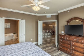 Une chambre à coucher avec un lit, une commode, un téléviseur et un ventilateur de plafond.