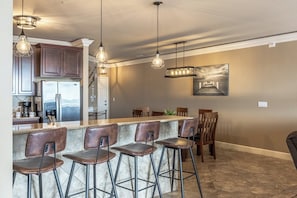 A modern kitchen with a bar area, stainless steel appliances, and pendant lighting.