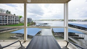 Een overdekt buitengebied met uitzicht op een wateroppervlak, zonnepanelen en een complex van gebouwen op de achtergrond.