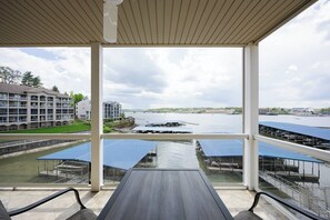 A covered outdoor area with a view of a body of water, solar panels, and a building complex in the background. - Lands End 637 - Three Bedroom Apartment, Sleeps 8 (Osage Beach)