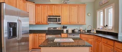 A kitchen with wooden cabinets, stainless steel appliances, a granite countertop, and a central island.
