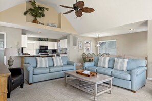 A spacious living room with two light blue sofas, a wooden coffee table, and a ceiling fan. - Dolphin Watch: Oceanside, Village at Nags Head (Nags Head)